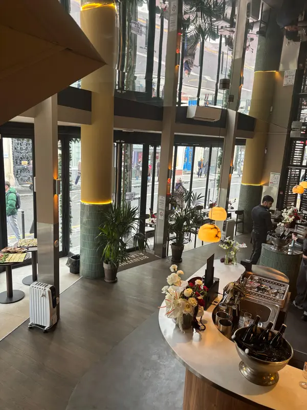 Modern Parisian restaurant interior with elegant bar, fresh flowers, champagne, and floor-to-ceiling windows overlooking the street.